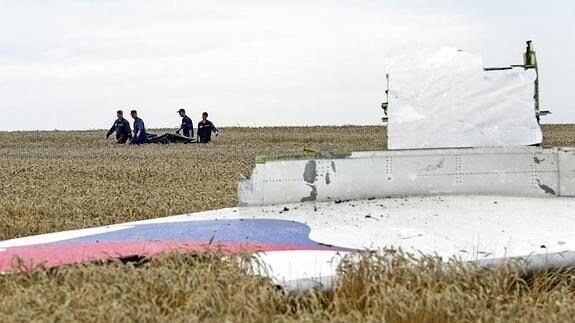 Varias personas transportan un cadáver en medio de los destrozos de un Boeing 777, vuelo MH17 de Malaysia Airlines. 