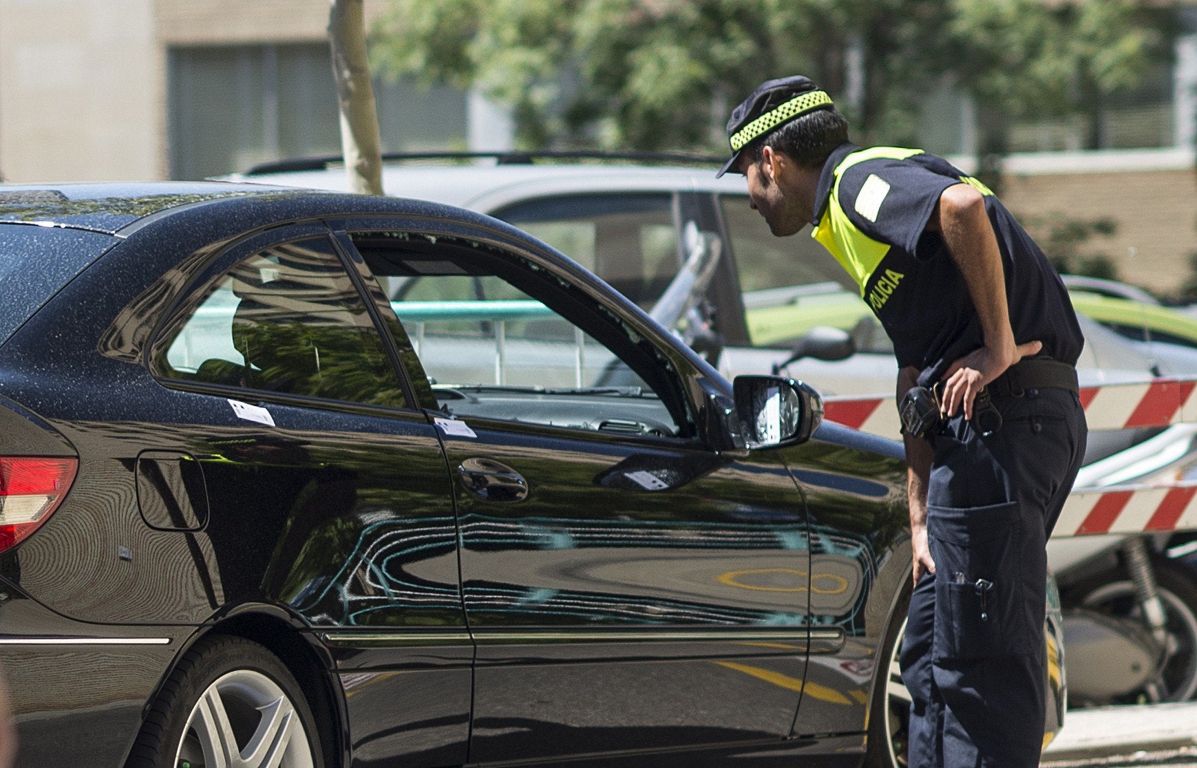 Un agente inspecciona el coche en el que circulaba la mujer atacada por su exmarido. 