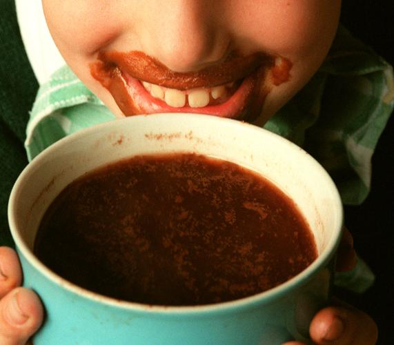 Un niño bebe una taza de chocolate. 