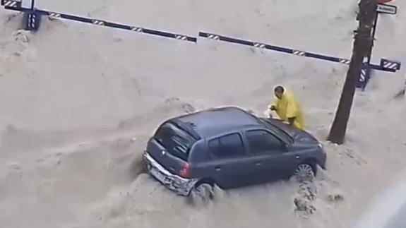 El varón de 65 años, junto a su coche en medio de la riada.