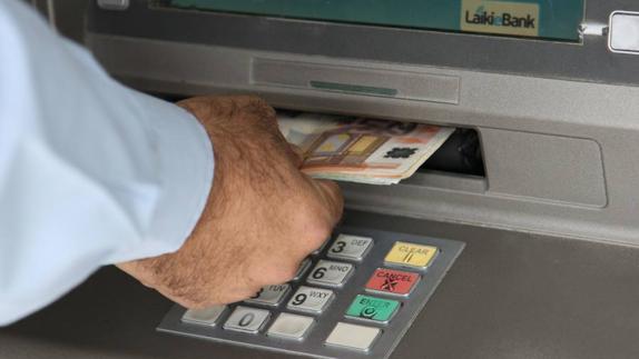 Un hombre saca dinero de un cajero automático.