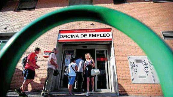 Ciudadanos hacen cola frente a una oficina de empleo.