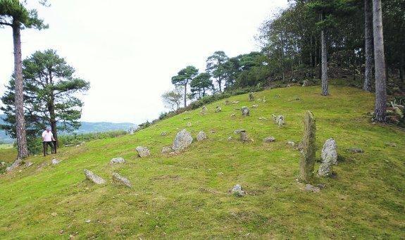 Un visitante lee las indicaciones escritas en el atril instalado al lado de los crómlech.