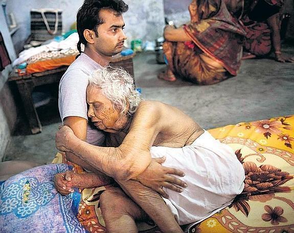 Divyesh Tiwari abraza a su abuela Bhogla Devi, de 97 años, en su habitación del Mukti Bhavan. 