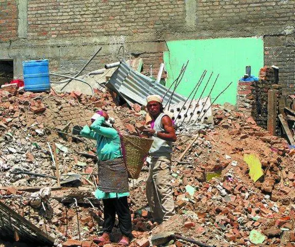 Una mujer porta una cesta llena de escombros.