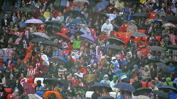 Aficionados del Athletic se resguardan de la lluvia durnate un partido en San Mamés.