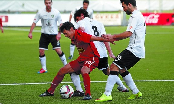 Control. Ozkoidi trata de proteger el esférico ante la presión de dos jugadores del Gernika ayer en Urbieta.