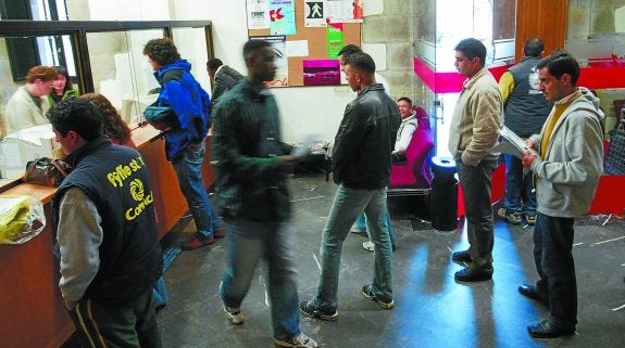 Un grupo de inmigrantes hace cola en una oficina de empadronamiento.