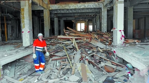 Un obrero, ante una montaña de madera, yeso y otros materiales extraídos del interior del edificio de la plaza de Lasala.