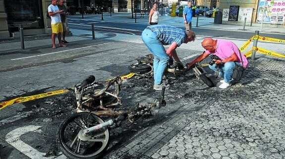 Dos agentes buscan indicios entre los restos de las dos motos que ardieron el pasado mes de agosto en el centro de San Sebastián.