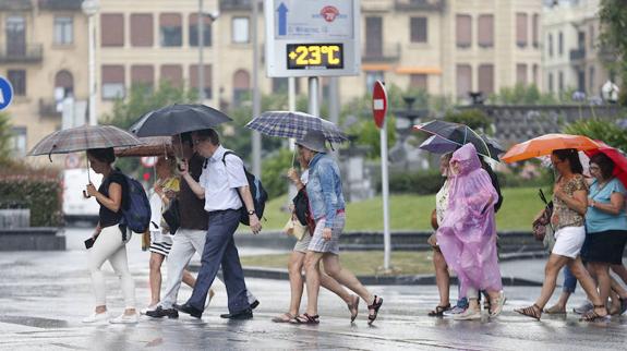 Varias personas caminan con paraguas tras un chaparrón caído el pasado agosto en Donostia