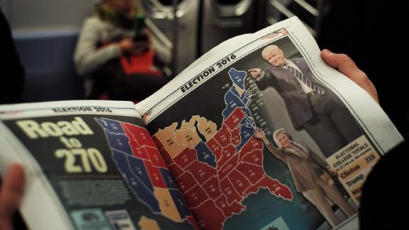 Un estadounidense lee la información de un periódico sobre las elecciones presidenciales