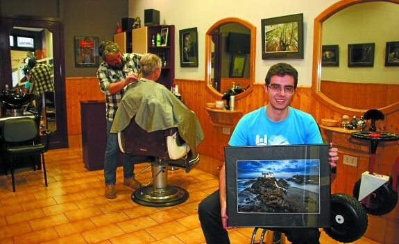 Gorka Gómez entre las fotografías que expone en la peluquería Juan Cruz hasta finales de diciembre.