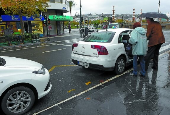 Dos clientes cogen un taxi en la parada del Boulevard.