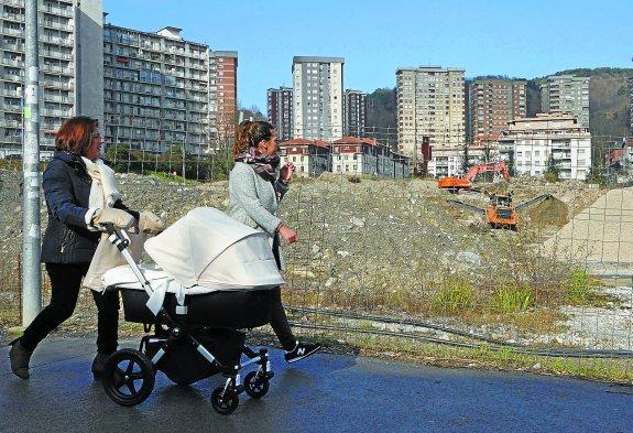 Dos mujeres observan cómo las máquinas mueven la tierra que el Ayuntamiento analizará para conocer su origen y composición.