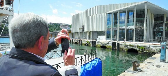 Un ciudadano saca una foto al edificio de la lonja de Pasaia, objeto de investigación.