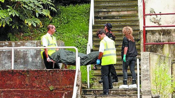 Miembros de la funeraria trasladan el cadáver.