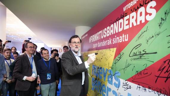 El presidente del Gobierno, Mariano Rajoy, firma en un panel, acompañado por el presidente del PP del País Vasco, Alfonso Alonso (i), durante la clausura del congreso del PP vasco celebrado hoy en Vitoria. EFE/David Aguilar