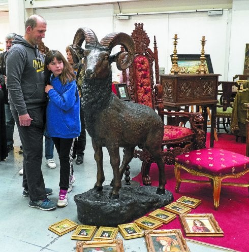 Carnero de bronce exterior, trono renacimiento y varias pinturas, en uno de los expositores de la Feria de Antigüedades.