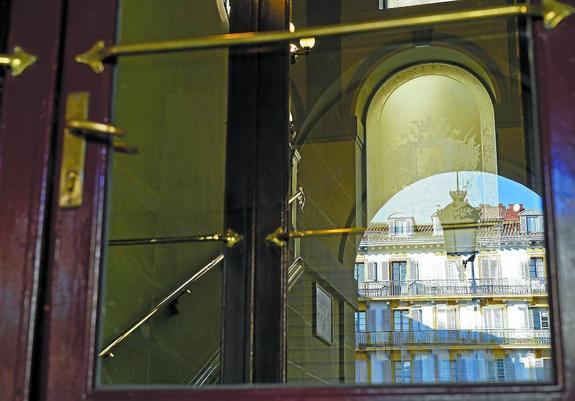 La plaza se refleja en el crista de la puerta que da acceso a la sede de la Unidad Técnica Central de Bibliotecas. 