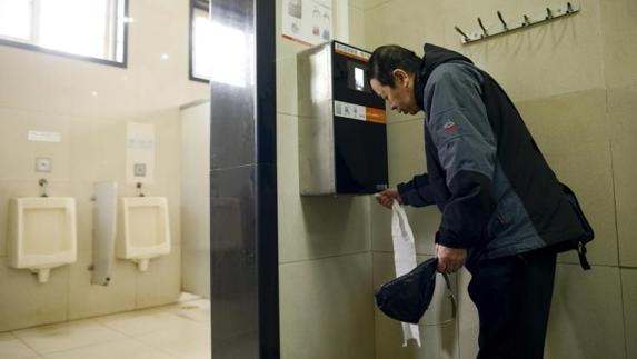 Un hombre hace uso de la máquina de reconocimiento facial que dispensa papel higiénico. 