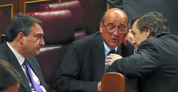 Los diputados del PNV Aitor Esteban y Mikel Legarda escuchan las explicaciones del portavoz del PP, Rafael Hernando, en el Congreso.