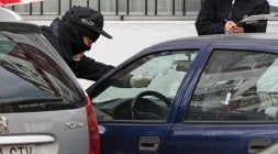 Un ertzaina examina los orificios del parabrisas del coche de la víctima tras los disparos realizados por el terrorista. [LOBO ALTUNA]