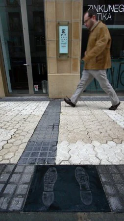 La baldosa y, al fondo, el optotipo para que donostiarras y extraños evalúen su agudeza visual. /GONTZAL LARGO El 'negrito' de Casa Paulista, más de una vida observando a varias generaciones de donostiarras.