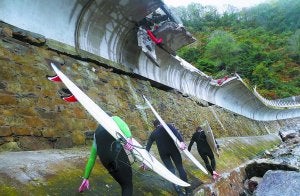 Tres surfistas sortean las piedras arrastradas por el oleaje al pie del paseo peatonal entre Zarautz y Getaria, de donde se desprendieron quince metros de muro. ::                             ETXEBERRIA