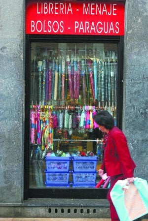 Una mujer pasa junto al escaparate de un bazar oriental. ::                             AYGÜES