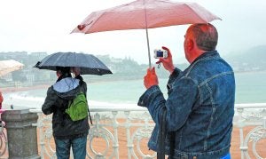 Vacaciones bajo el paraguas. Un turista fotografía la bahía de La Concha bajo la lluvia de julio. ::                             NAGORE IRAOLA