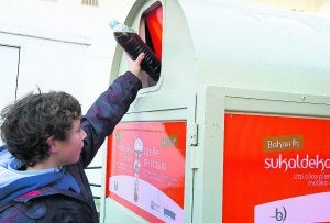 Un niño deposita una botella con aceite usado en el contenedor correspondiente. ::
J. I. UNANUE