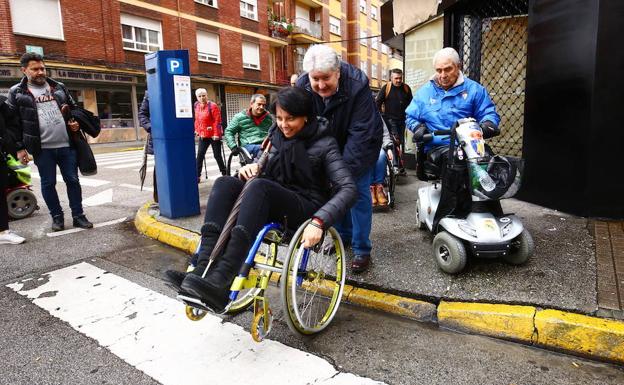 El concejal Ricardo Miranda ayuda a la edil Rosa Luna a bajar un bordillo.