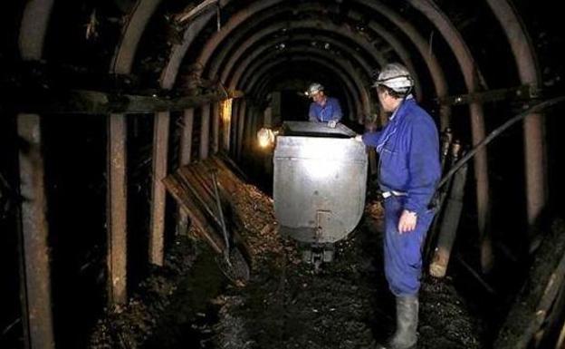 Dos mineros extraen carbón de un pozo. 