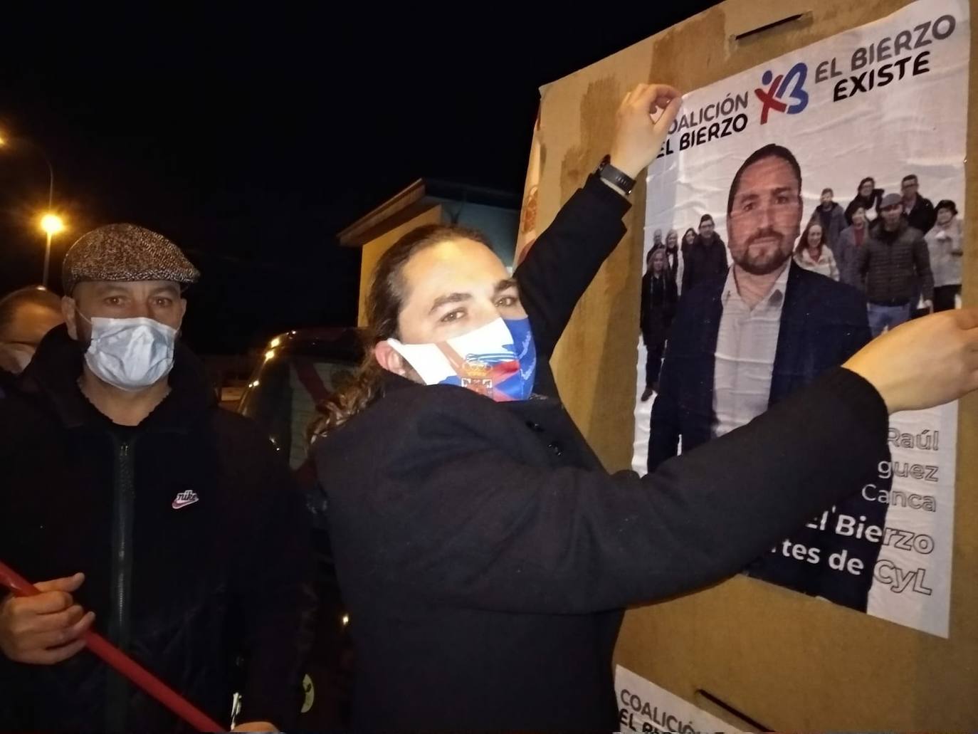 El cabeza de lista de CB, Raúl Rodríguez Canca, y el número cuatro, Luciano Arias, portavoz de El Bierzo Existe, en la pegada de carteles en San Andrés de Montejos.