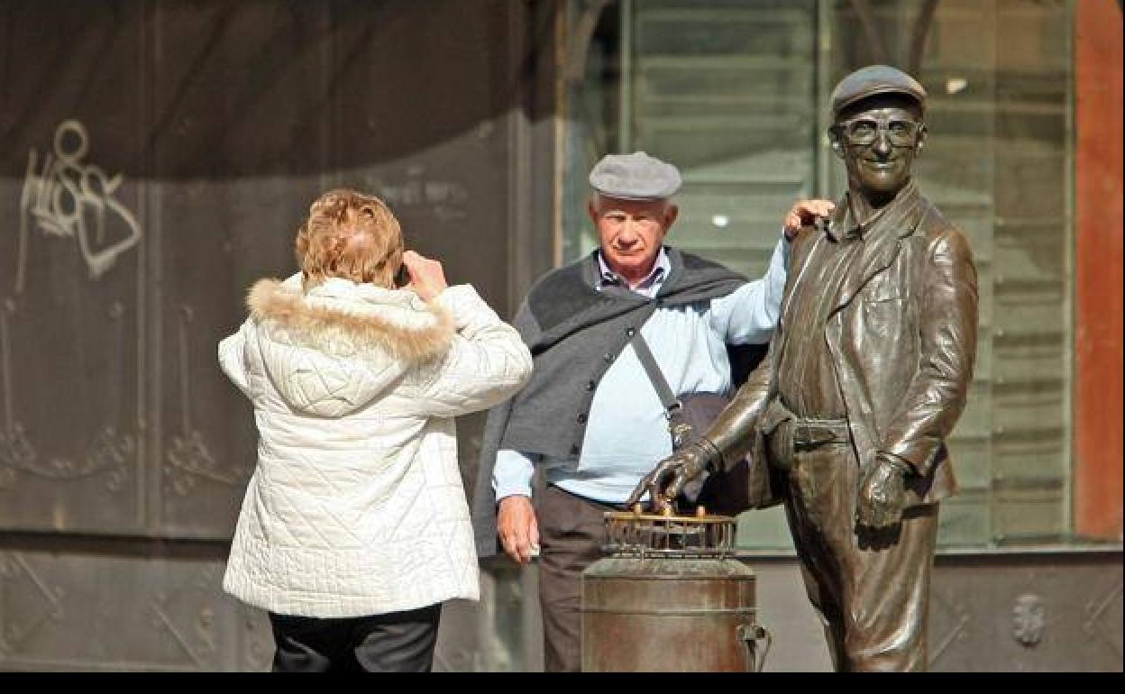 Imagen de archivo de dos turistas fotografiándose con la estatua del barquillero en Ponferrada.