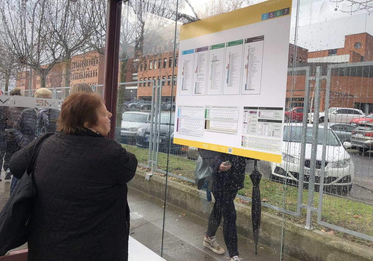 Imagen principal - De arriba abajo: una mujer se informa de los horarios del autobús; usuarios subiendo al transporte público y uno de los paneles de la parada del hospital.