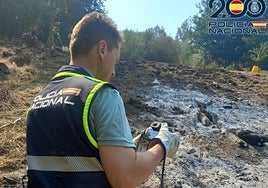 Un agente de la Policía Nacional realiza la inspección técnico-policial en la zona del incendio en Bouzas.