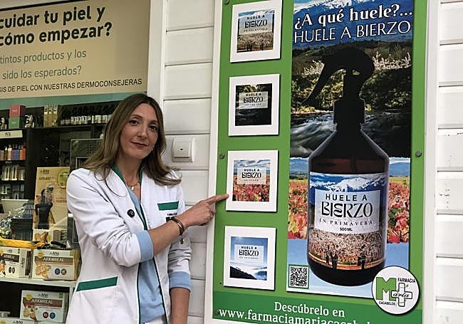 La propietaria de la Farmacia María de Cacabelos muestra el anuncio de las fragancias a la entrada del establecimiento ubicado en la plaza Mayor.