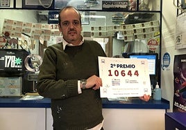 José Luis Salas muestra el cartel con el número agraciado con el segundo premio en el sorteo de la Lotería Nacional del que vendió cinco décimos en su administración.