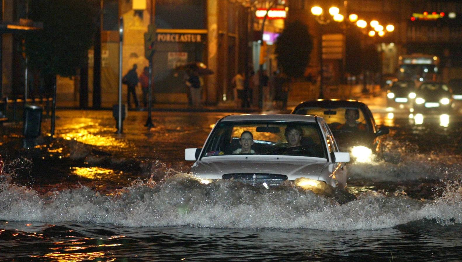 Dos coches circulan por la avenida de la Costa, en la Puerta la Villa, inundada tras las fuertes lluvias caídas en Gijón. 13/09/2006