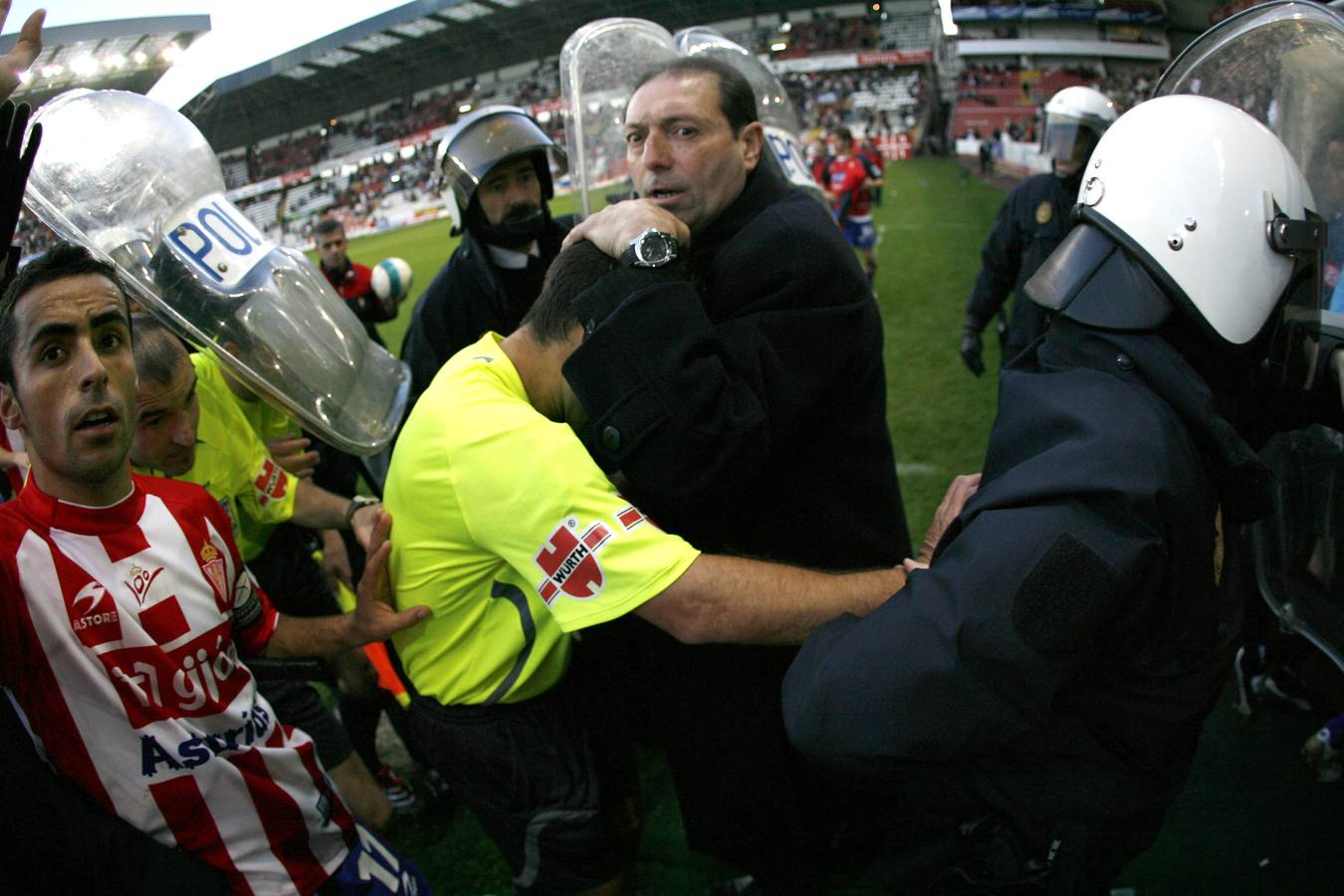 Enrique Castro 'Quini' protege al árbitro Paradas Romero de las iras de los aficionados del Sporting en su camino al túnel de vestuarios al final del partido contra el Elche. 18/02/2007