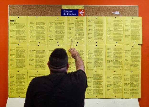 Un joven analiza las ofertas de empleo colgadas en el tablón de anuncios de una oficina asturiana del Servicio Público de Empleo. 
