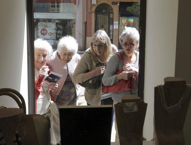 Un grupo de mujeres cruceristas observa el escaparate de una tienda en una escale en Avilés. 