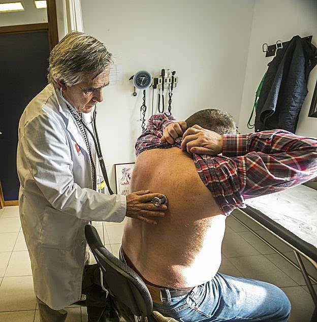 Un médico ausculta a un paciente en su consulta. 