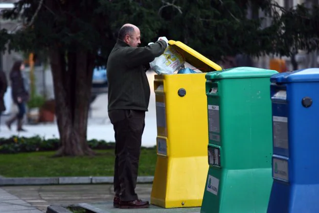 Un vecino depostita una bolsa en un contenedor de envases. 