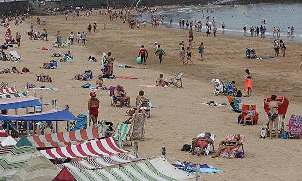 Bañistas en la playa de San Lorenzo a pesar del día cubierto. 