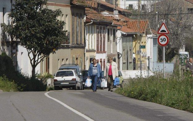 Dos mujeres caminan por la calzada con la compara en la zona de Piqueros. 