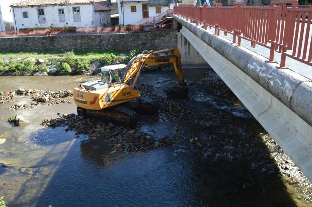 Una máquina trabaja en la limpieza del cauce del río Narcea. 