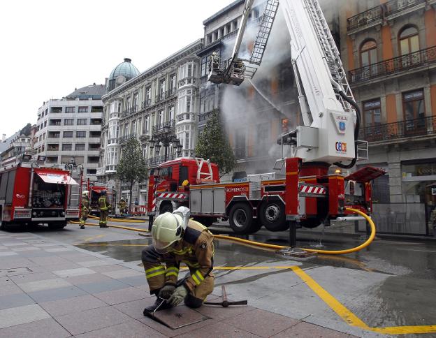 Un bombero trata de localizar una boca de incendios durante el fuego de Uría, 58. 